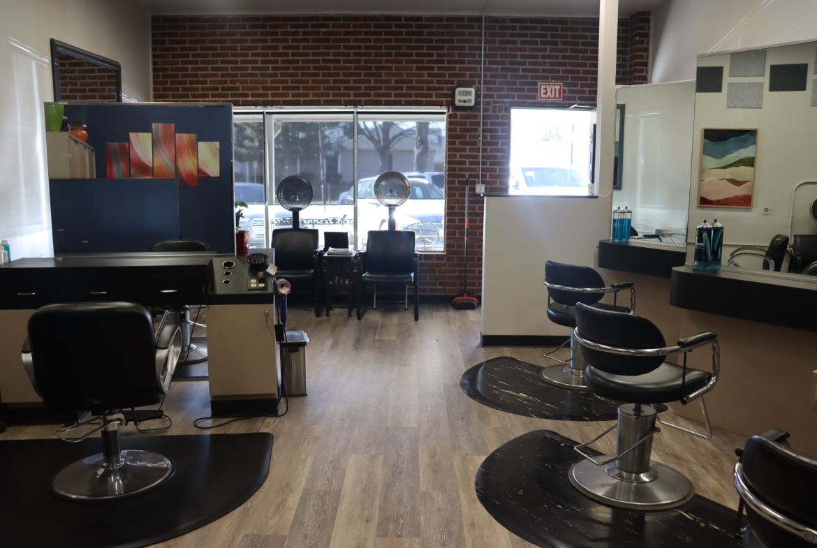 Bright salon with black chairs, hair dryers, and contemporary decor for hair styling.