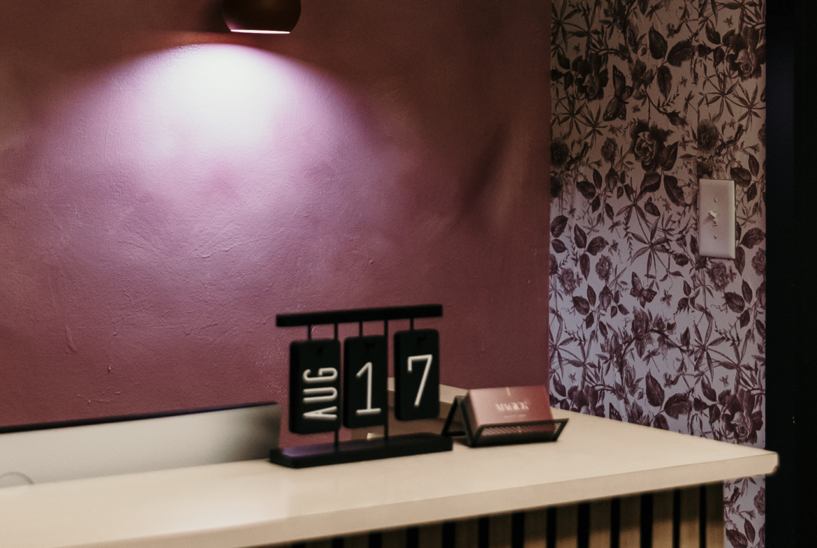 Bright lighting, floral wallpaper, and reception desk at a trendy salon for a welcoming atmosphere.