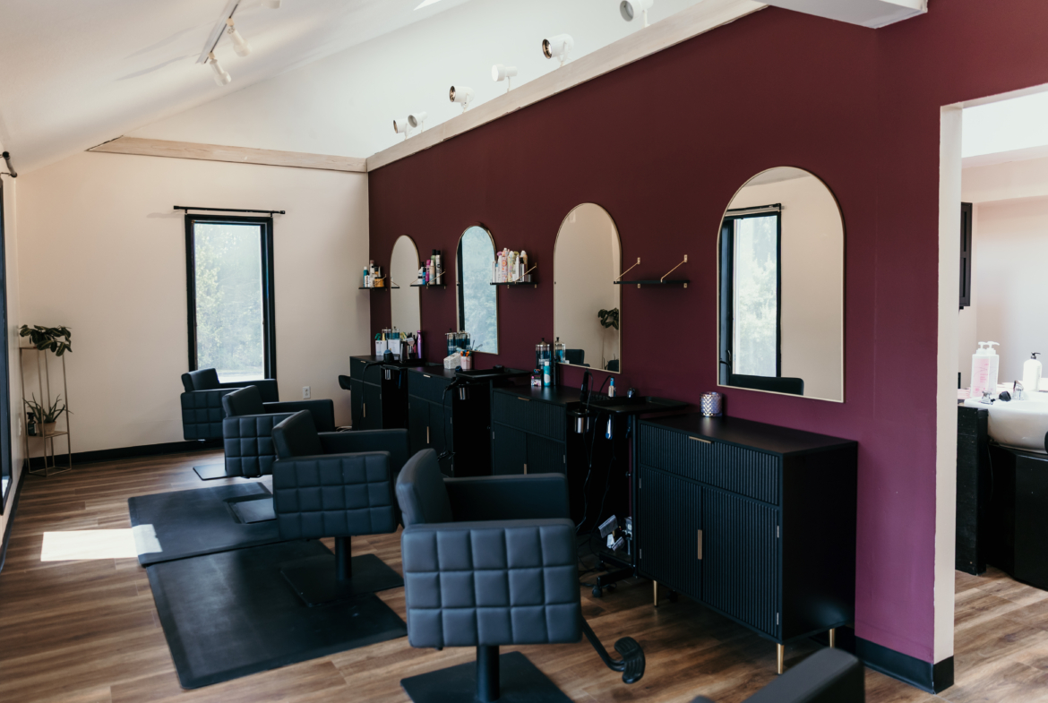 Stylish salon interior with black styling chairs, mirrors, and hair product displays for beauty professionals.
