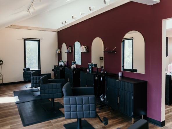 Stylish salon interior featuring Black chairs, mirrors, and hair product shelves for beauty services.