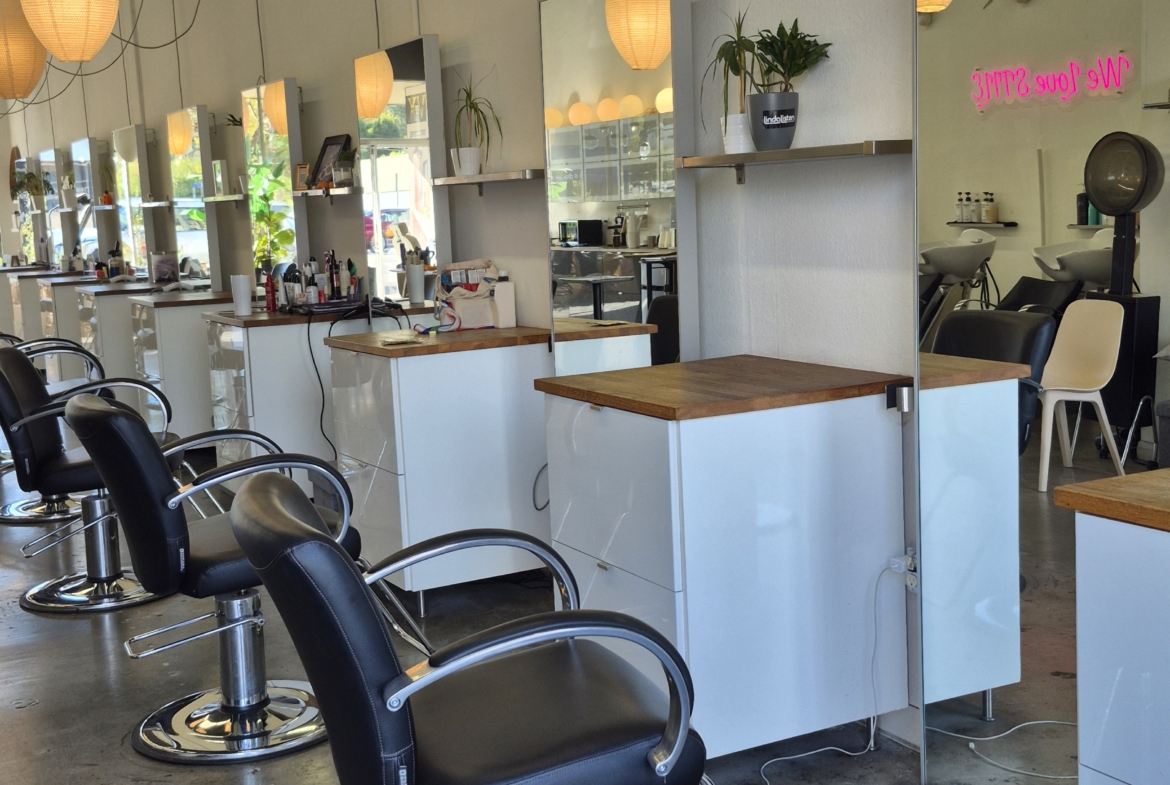Modern salon workstations with chairs, mirrors, and lighting for hair styling.
