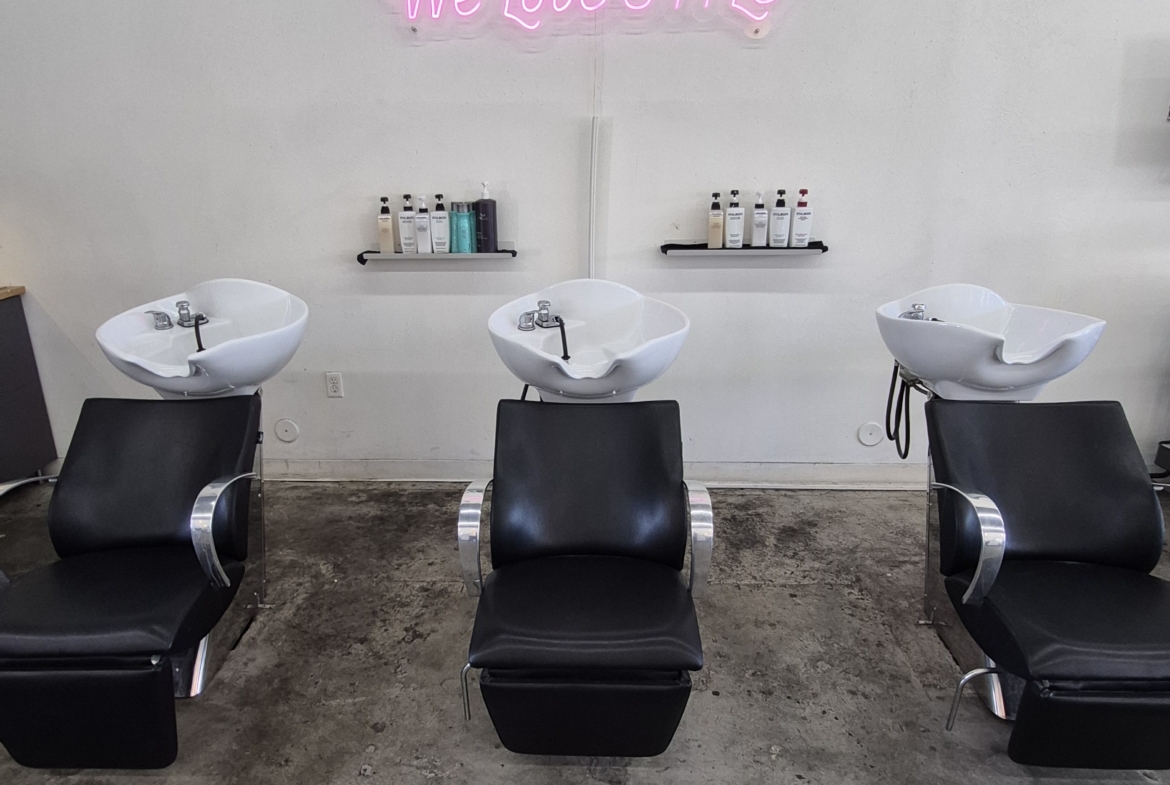 Stylish hair washing stations featuring comfortable chairs and sleek basins in a trendy salon environment.