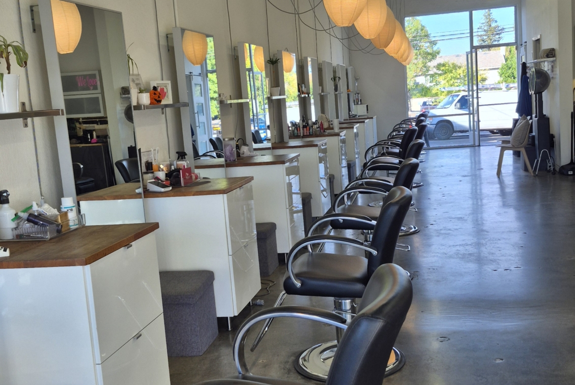 Clean salon station with comfortable black chairs and mirror stations for beauty treatments.