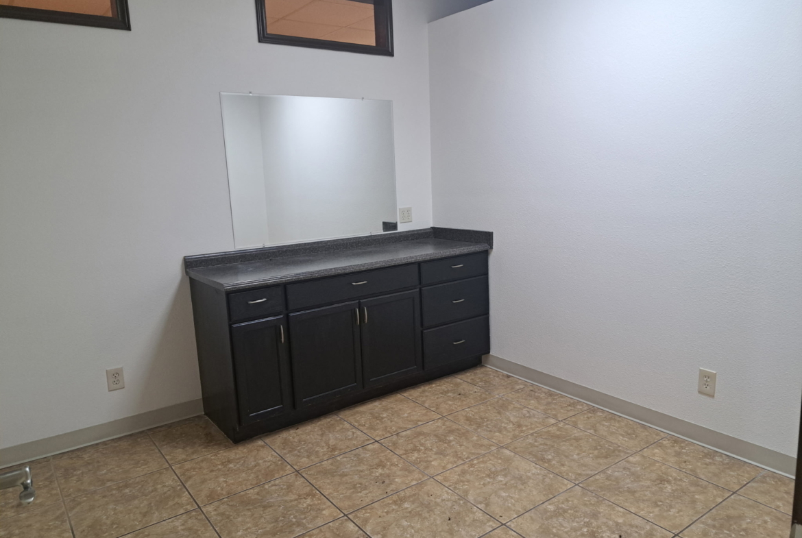 Bright salon space featuring a sleek black island and clean white walls for rent.