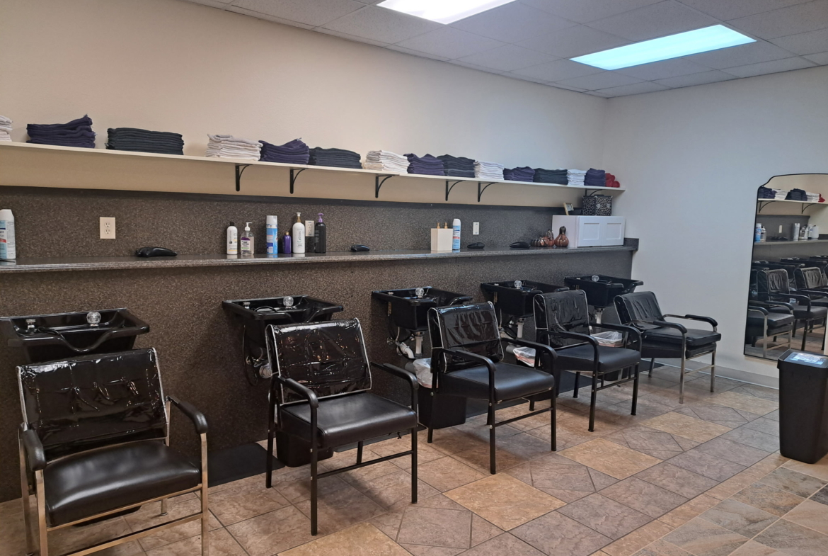 Clean hair salon wash basin area with styling chairs and professional tools, ideal for salon rental.