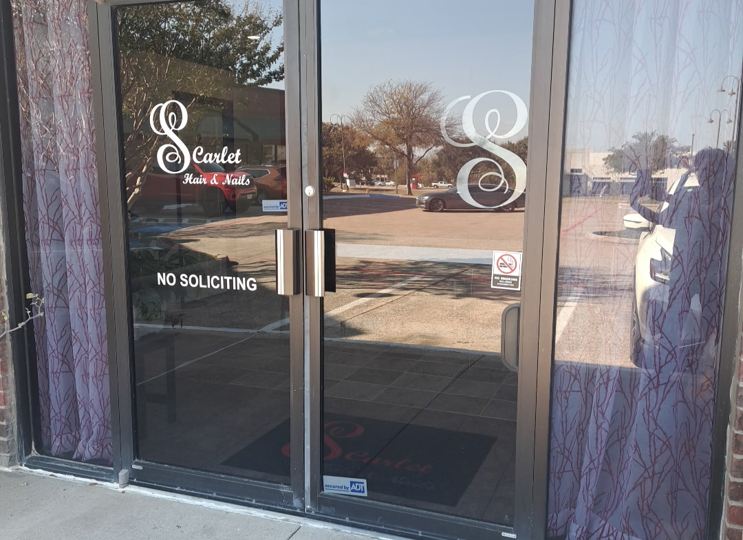 Modern salon building entrance featuring glass doors and branding signage for hair and nail services.