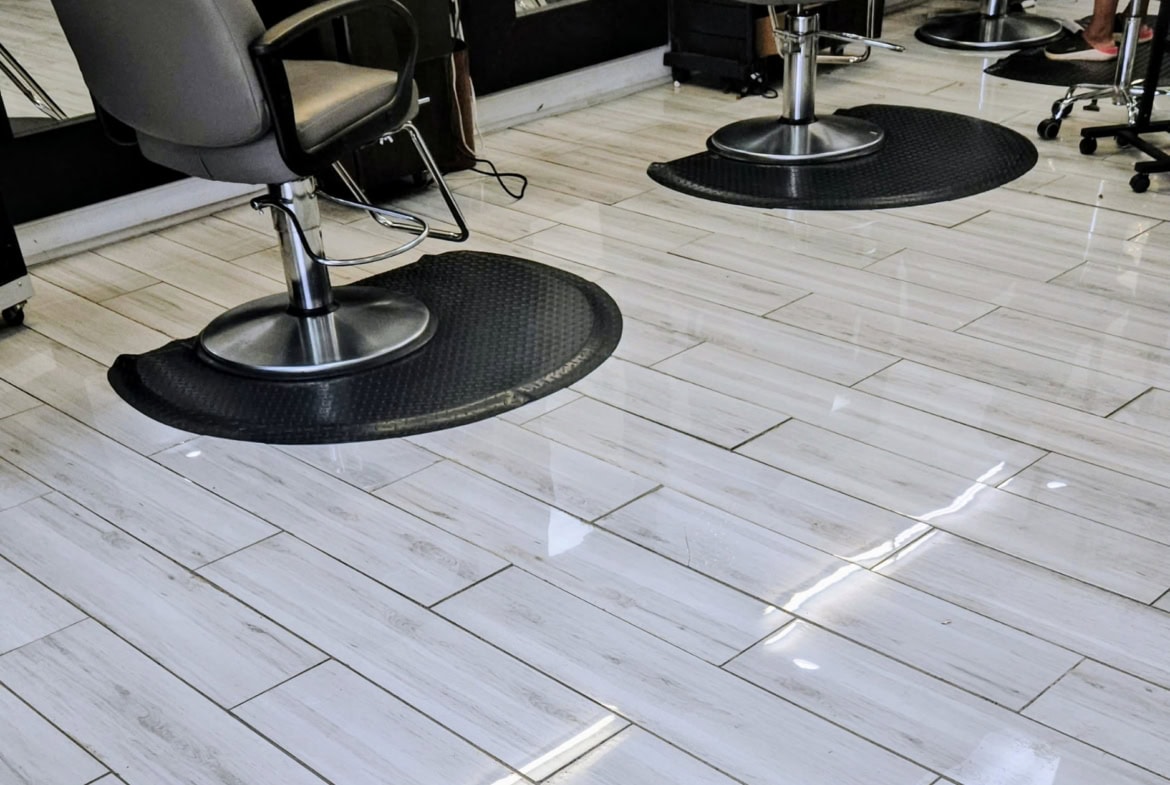 Comfortable salon chairs on black mats in a modern hair salon.