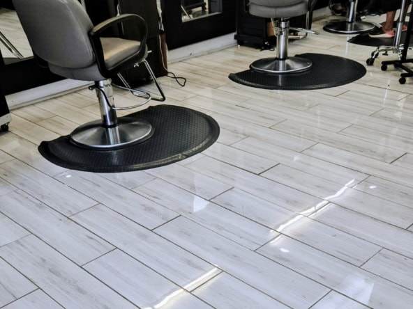 Comfortable salon chairs on black mats in a modern hair salon.