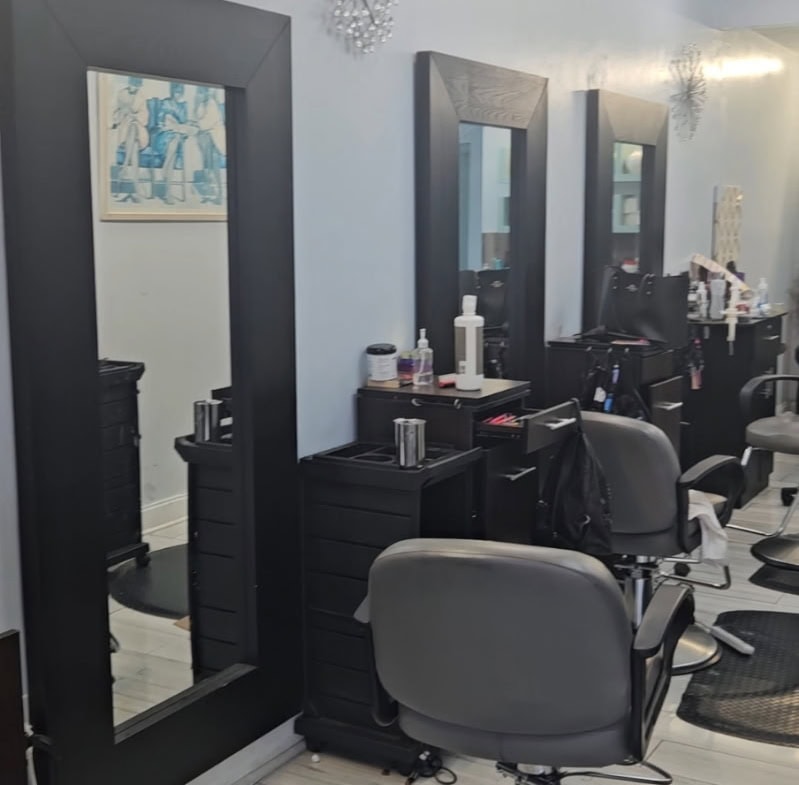 Clean professional hair salon station with mirrors, styling chairs, and salon tools.