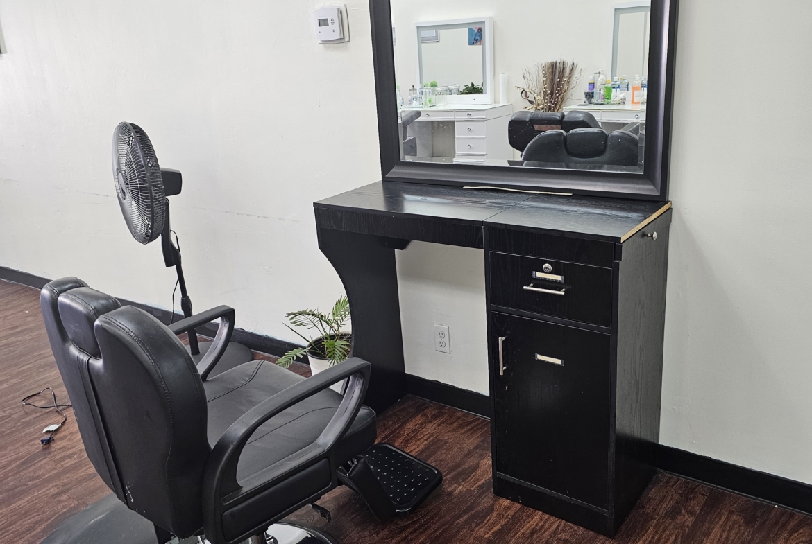 Stylish salon styling station with mirror and black furniture for beauty professionals.