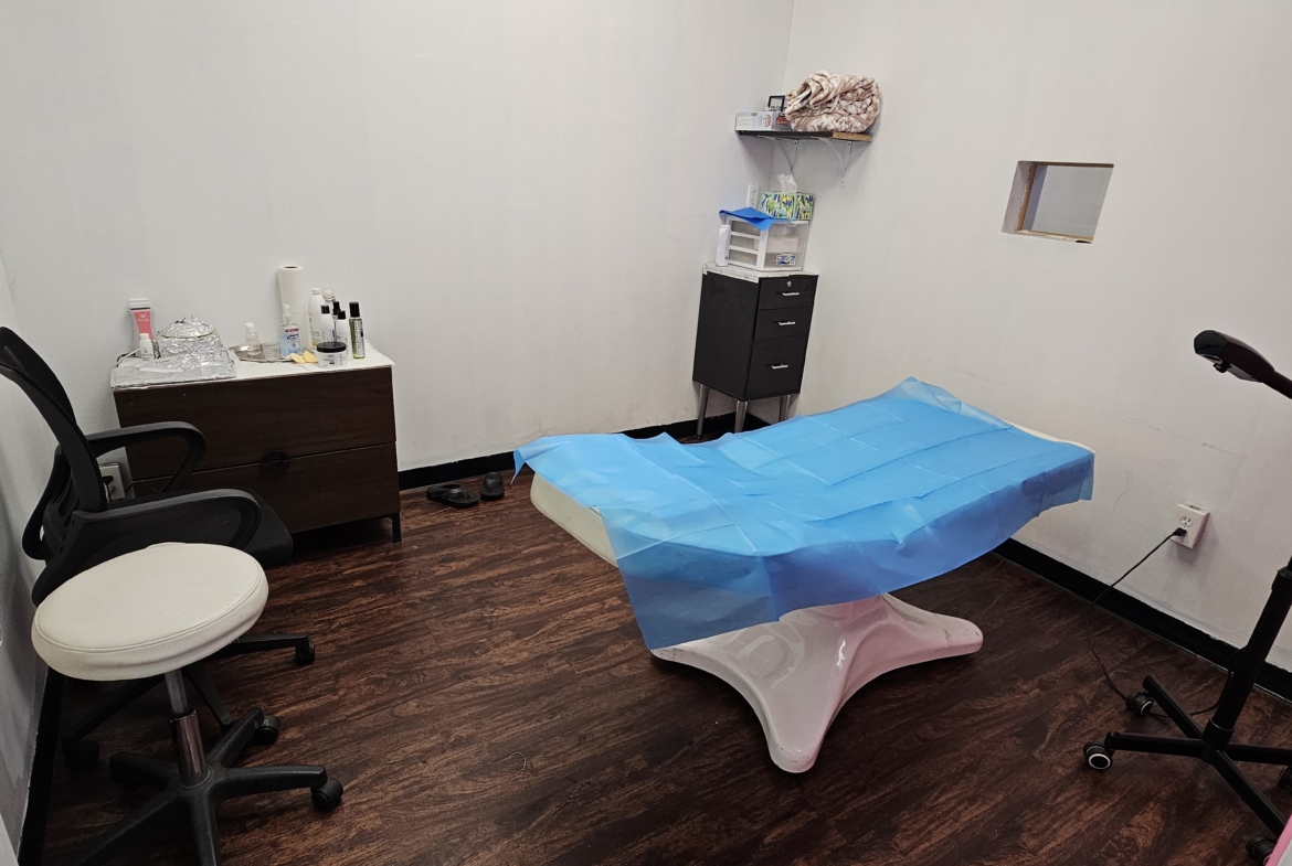 Clean, simple salon renting space with treatment bed, chairs, and storage.