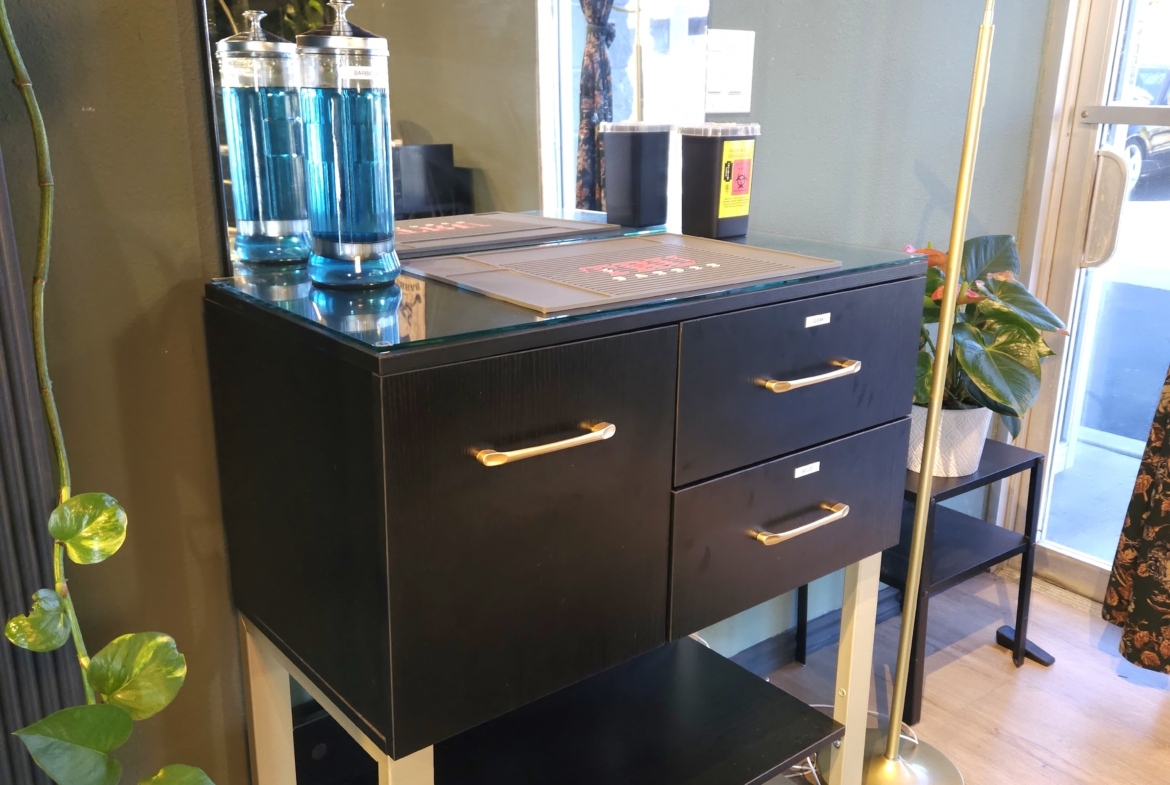 Salon station with black cabinetry, gold accents, and a large mirror in a stylish hair salon.