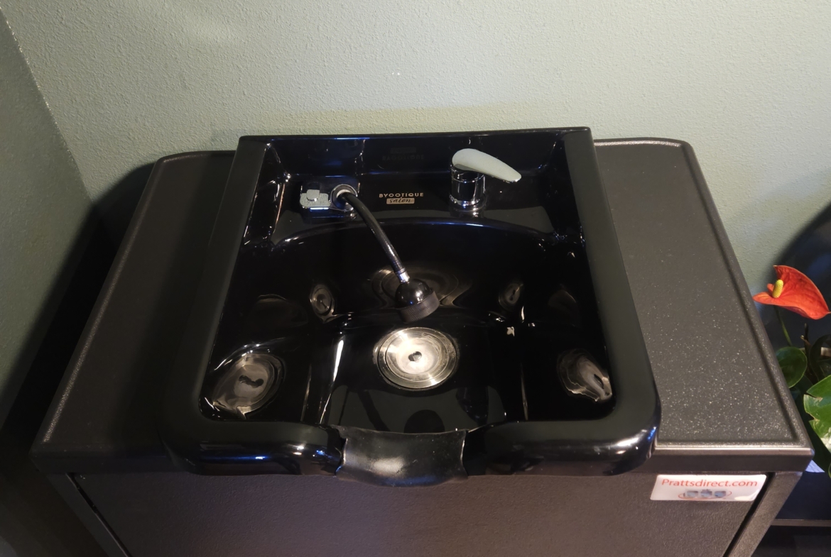 Black salon sink for shampooing and hair washing, professional hairdresser equipment.