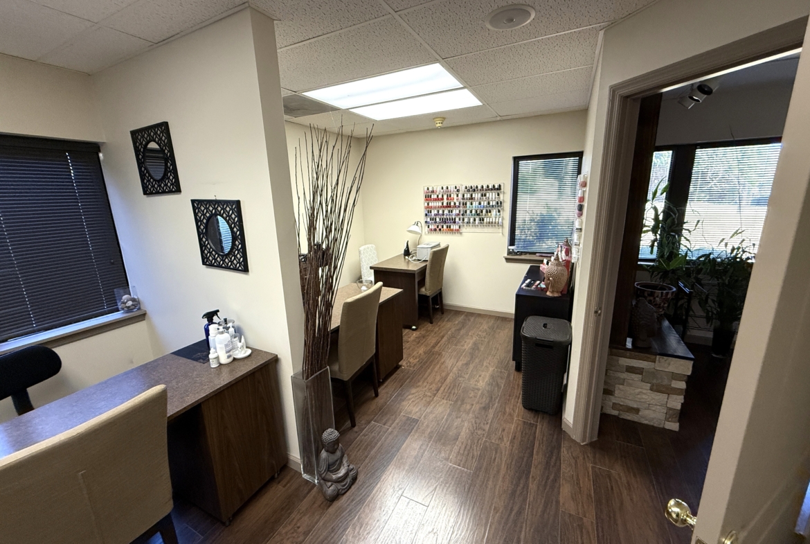 Elegant interior of a salon workspace with nail polish racks, desks, and decorative accents for client comfort.