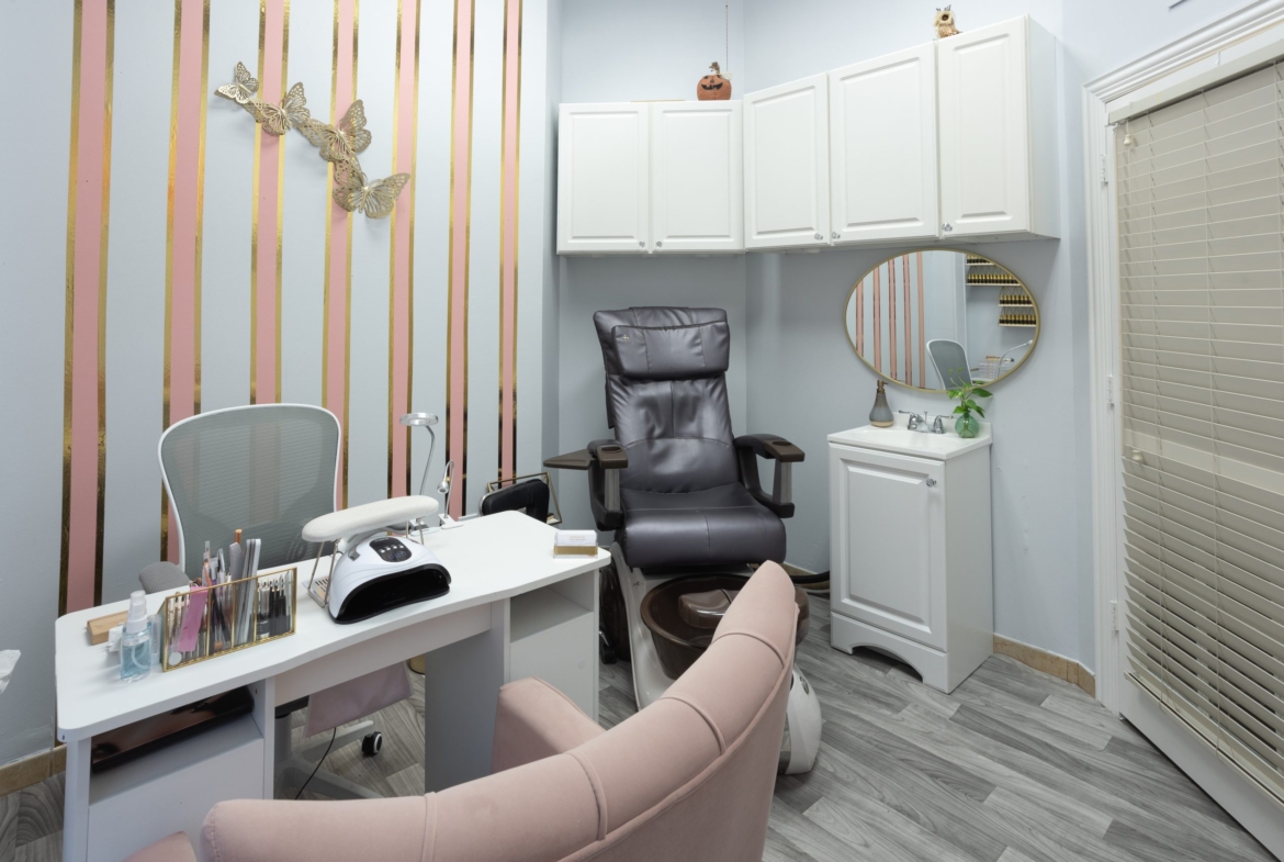 An inviting salon room featuring a comfy pink chair, skincare station, and decorative butterfly wall art for clients' comfort.