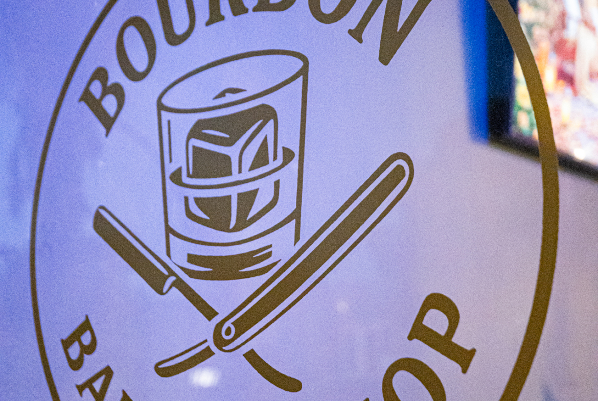 Close-up of Bourbon Barbershop sign with whiskey glass and straight razor.