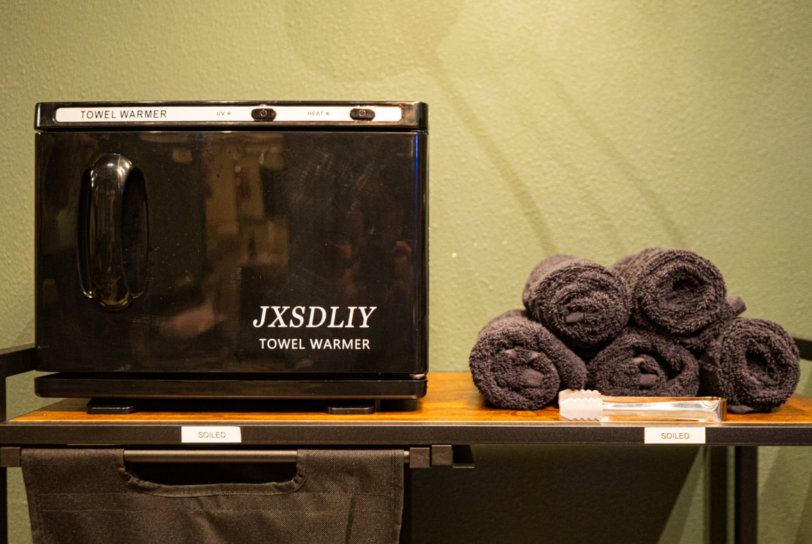 High-quality towel warmer for salons and spas, with neatly rolled black towels and professional amenities.