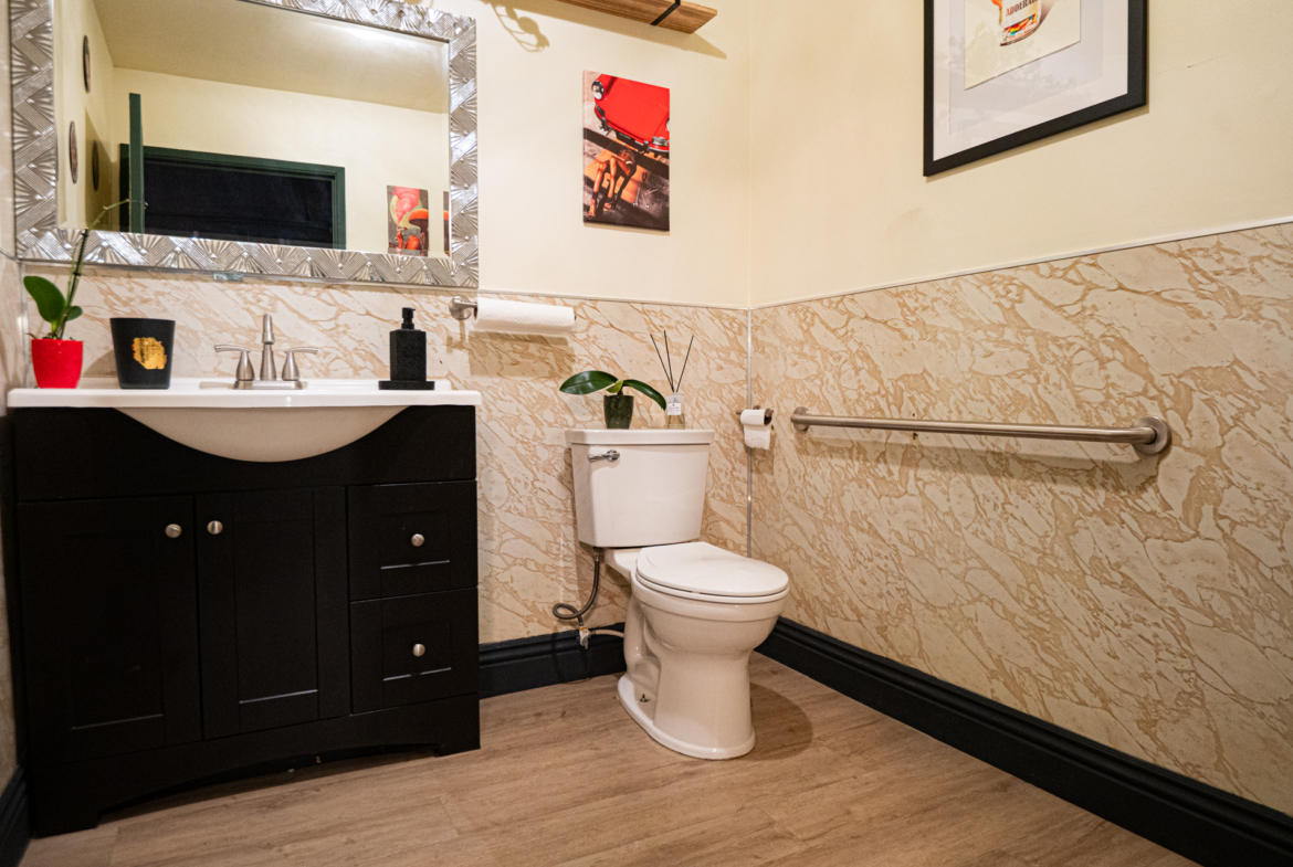 Spacious bathroom featuring a sleek black vanity, decorative wall art, and accessibility features.