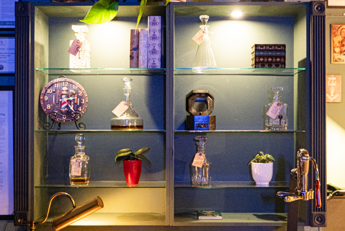 Bright interior decor featuring decorative glass bottles, plants, and artwork at salon space.