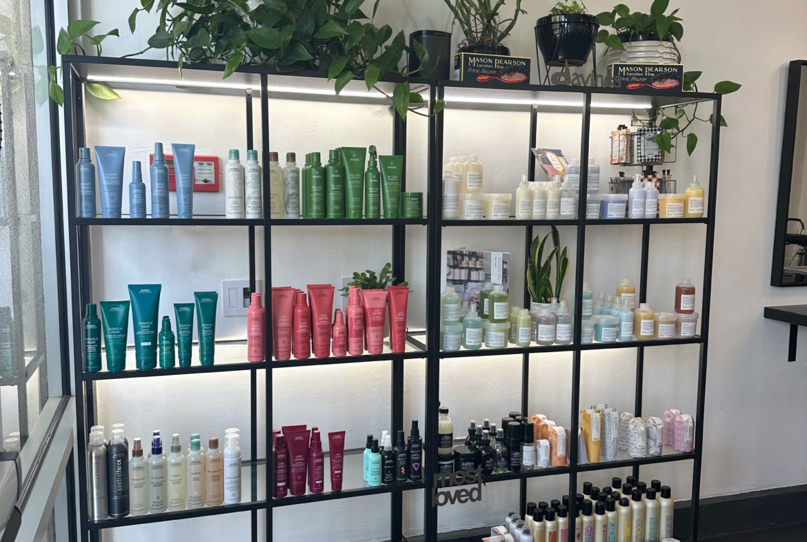 Colorful hair care products on a black metal shelf at a salon.