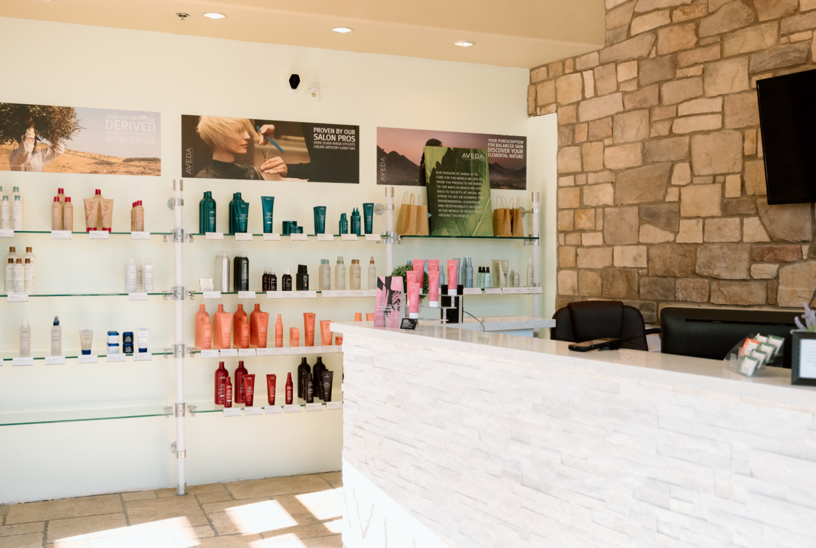 Bright salon reception with hair and beauty product shelves, modern décor, and inviting atmosphere.