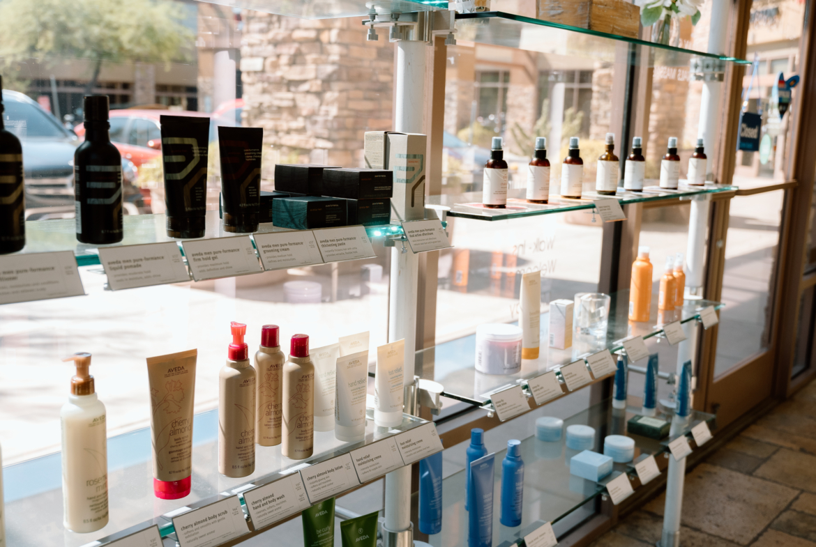Bright salon retail shelves showcasing hair and skincare products with natural sunlight.