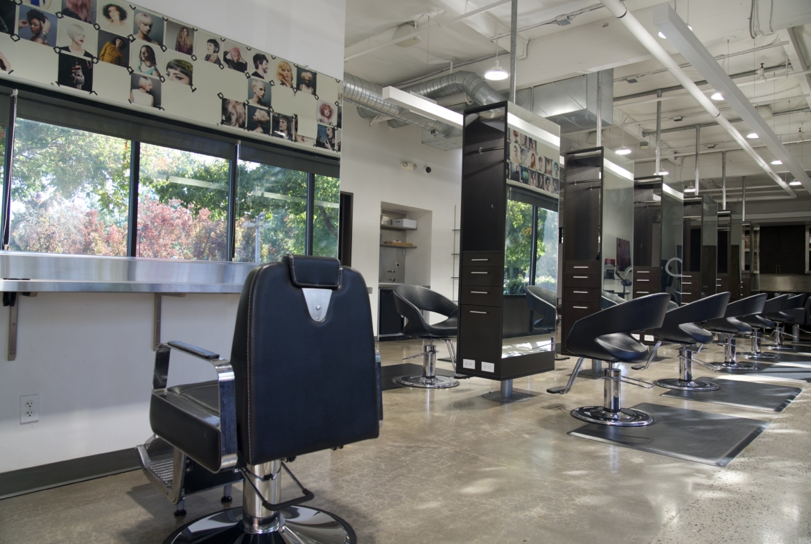 Bright salon interior with black styling chairs and large windows for natural light.