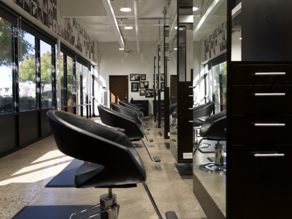Picture of a stylish, well-lit salon interior featuring sleek black chairs, large windows, and organized stations for hair styling services.