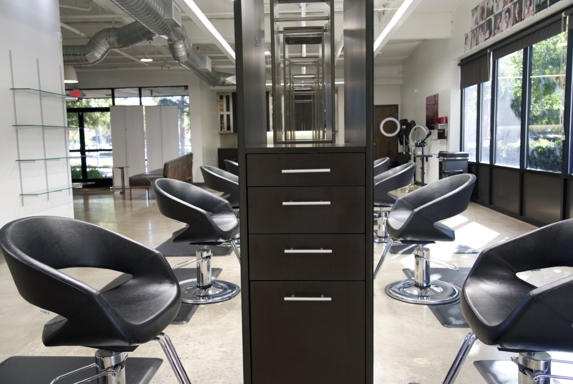 Bright hair salon with modern styling chairs and ample natural light streaming through large windows.