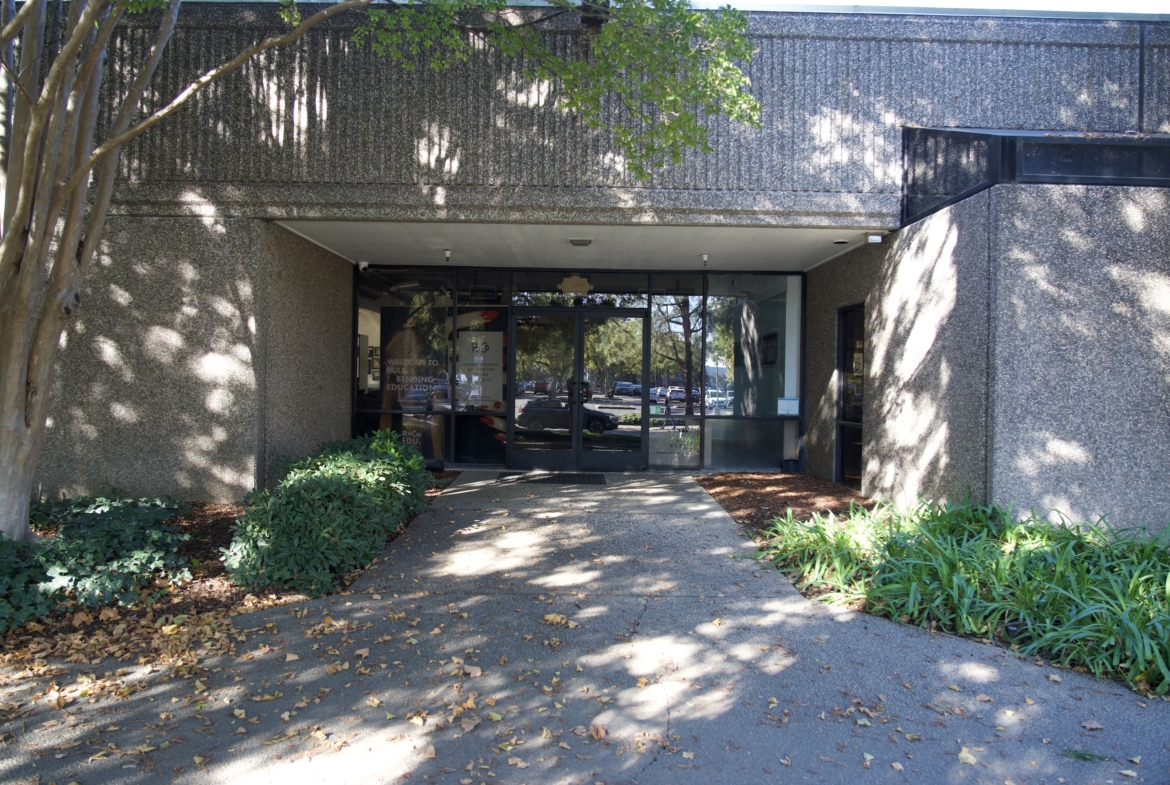 Easy access office space with modern glass entrance, surrounded by greenery and shade trees for professional work environment.