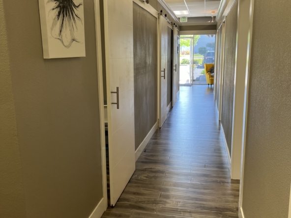 Bright salon corridor with private rental spaces, wood flooring, and modern interior design.