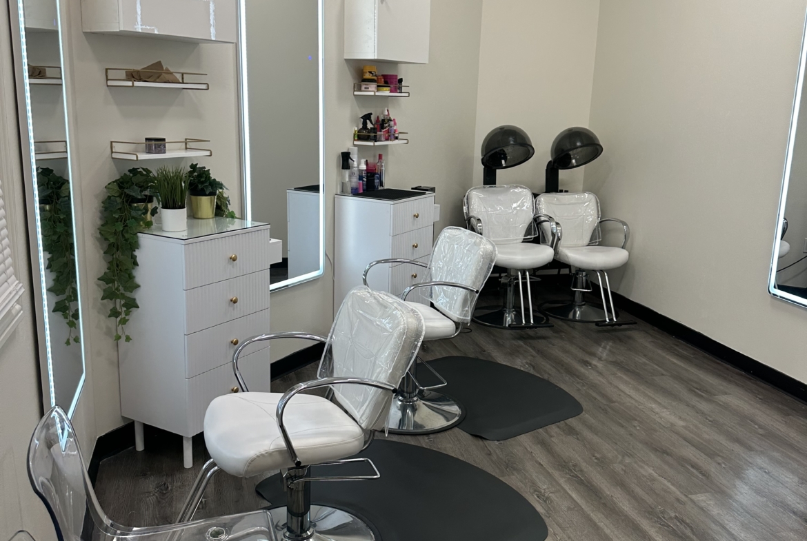 Bright salon interior featuring styling chairs, mirrors, and hair washing units.