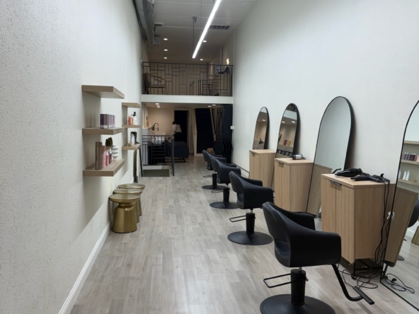Interior of stylish hair salon with barber chairs and large mirrors.
