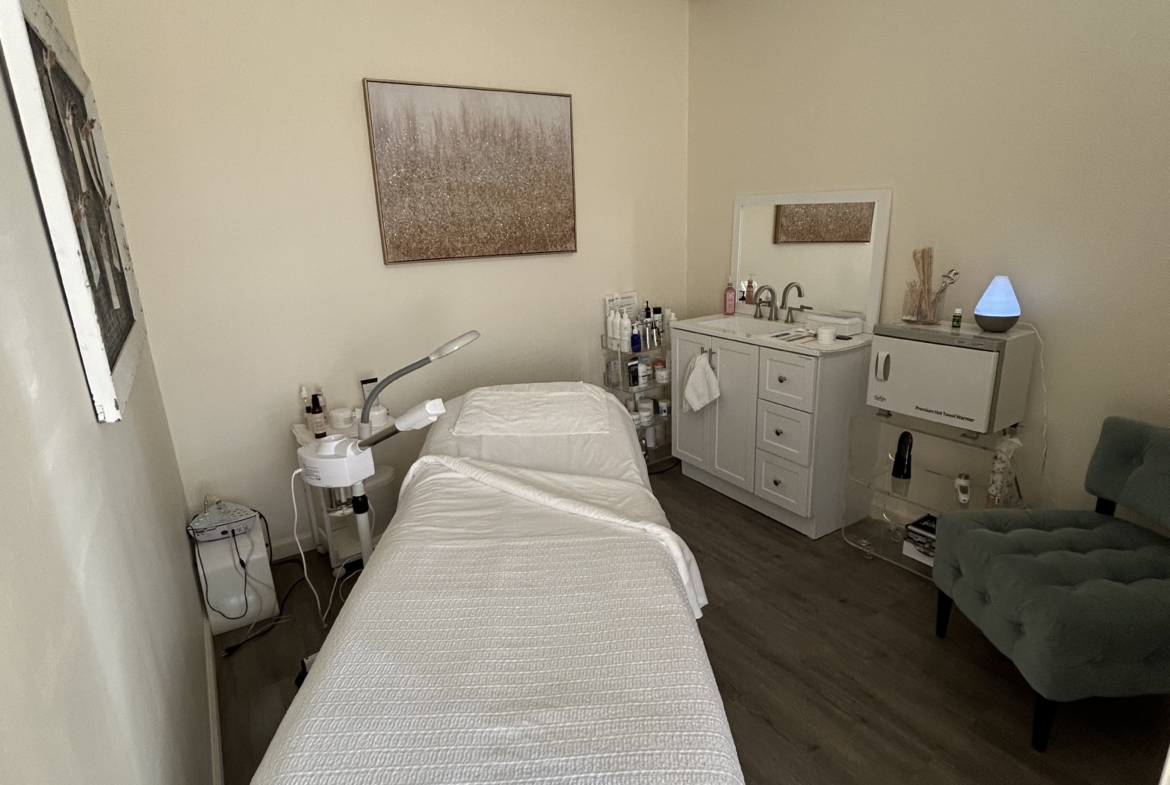 Comfortable salon treatment room with massage bed, skincare products, and calming atmosphere.
