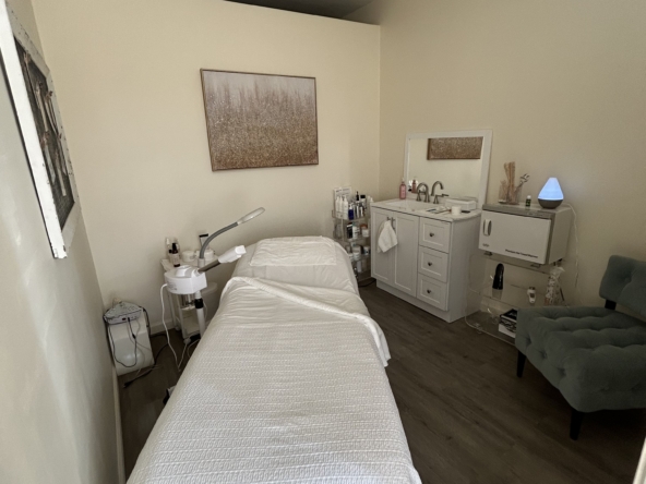 Comfortable salon treatment room with massage bed, skincare products, and calming atmosphere.