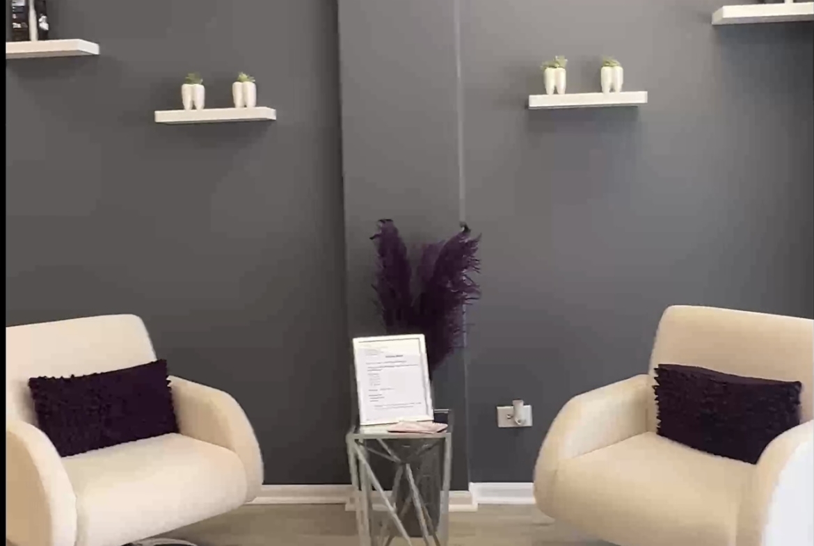 Comfortable salon lounge with contemporary chairs, purple accents, and decorative shelving.