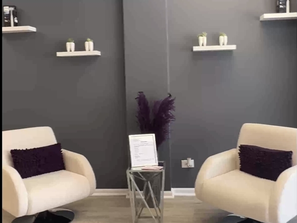 Comfortable salon lounge with contemporary chairs, purple accents, and decorative shelving.