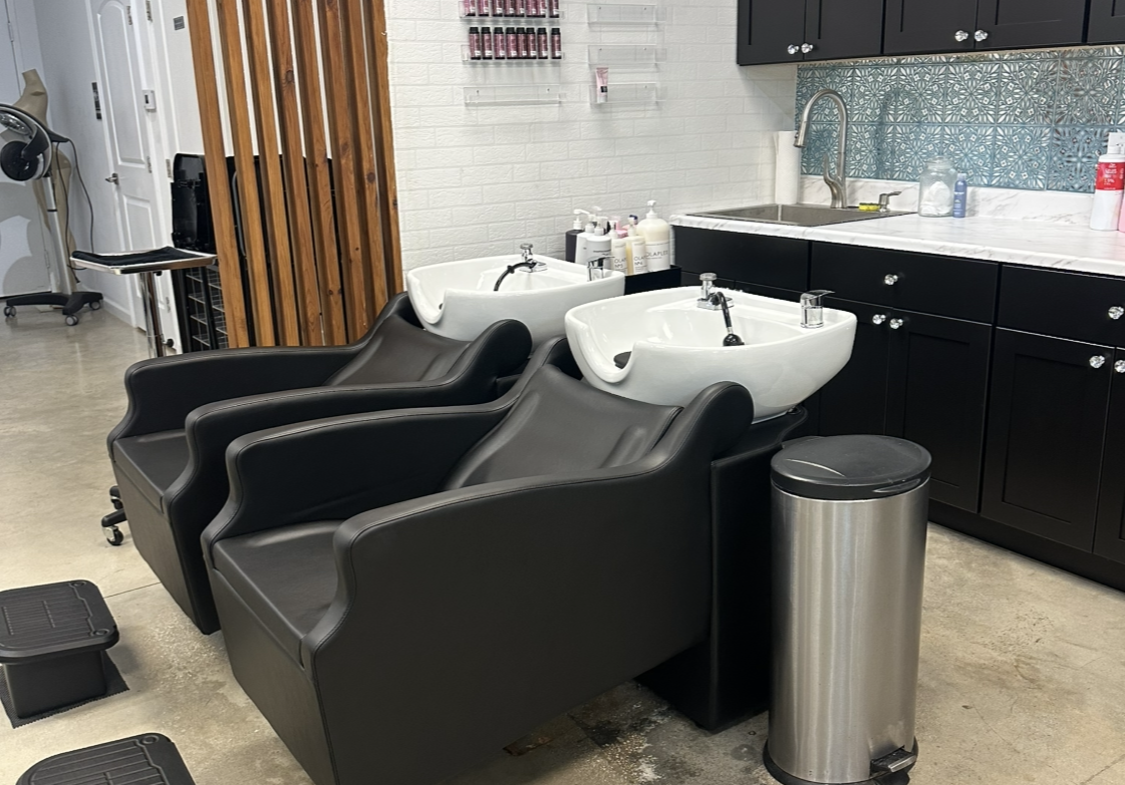 Comfortable hair washing area with black salon chairs and sink stations.