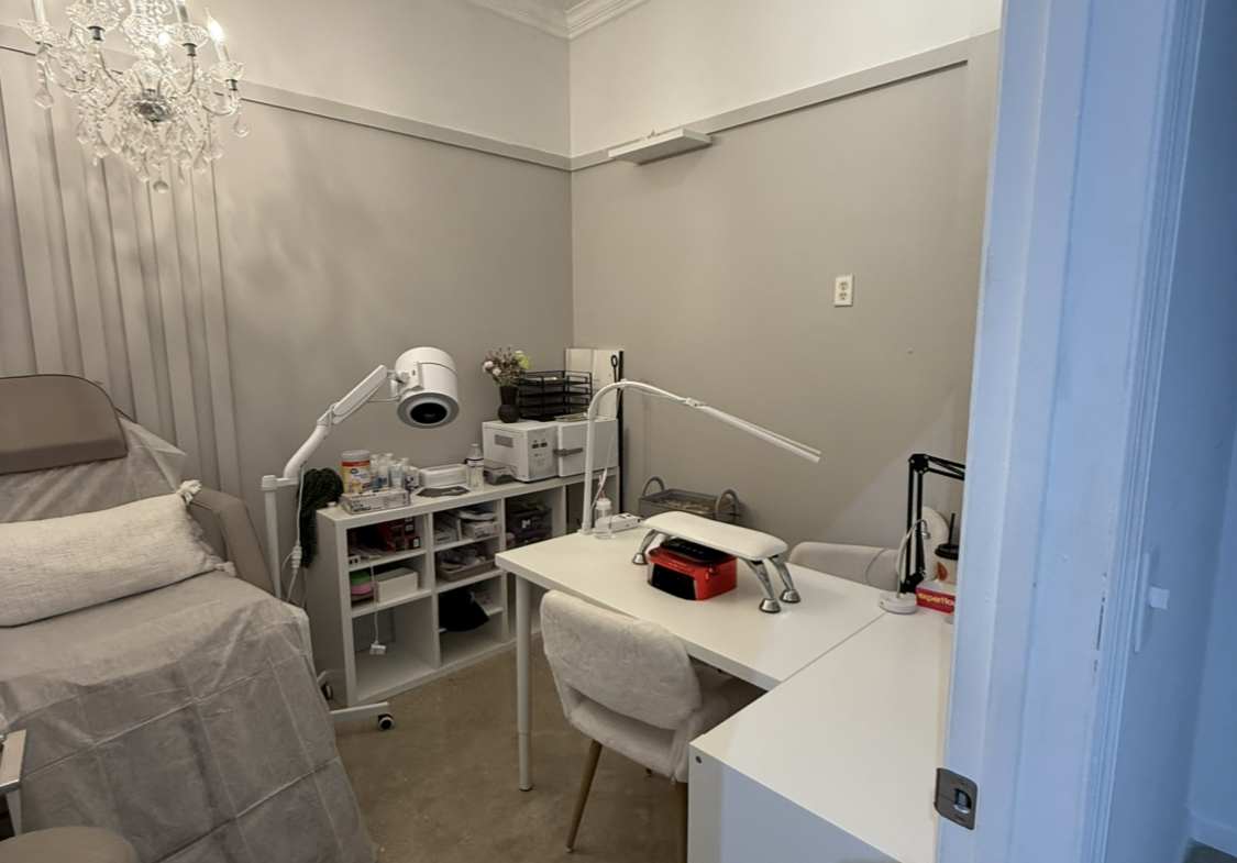 A professional salon rental space featuring a manicure station, cozy decor, and modern equipment.