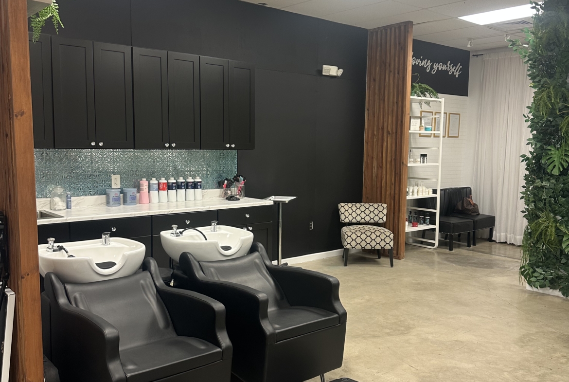 Stylish salon wash stations with comfortable black chairs and sinks.