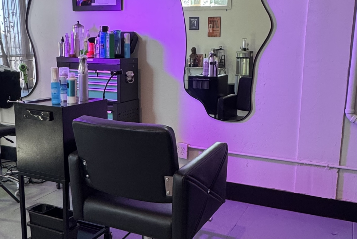 Bright salon workspace featuring unique mirror design, styling chair, and beauty products.