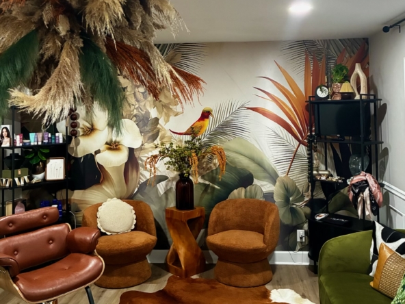 Elegant salon lounge featuring tropical botanical wallpaper and stylish furniture.