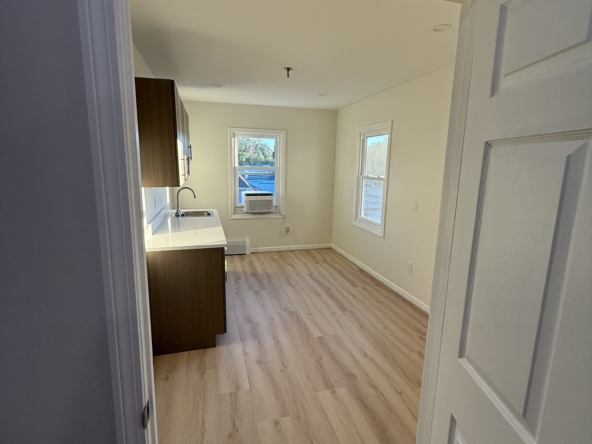 Bright, empty salon rental space with windows and hardwood floors.