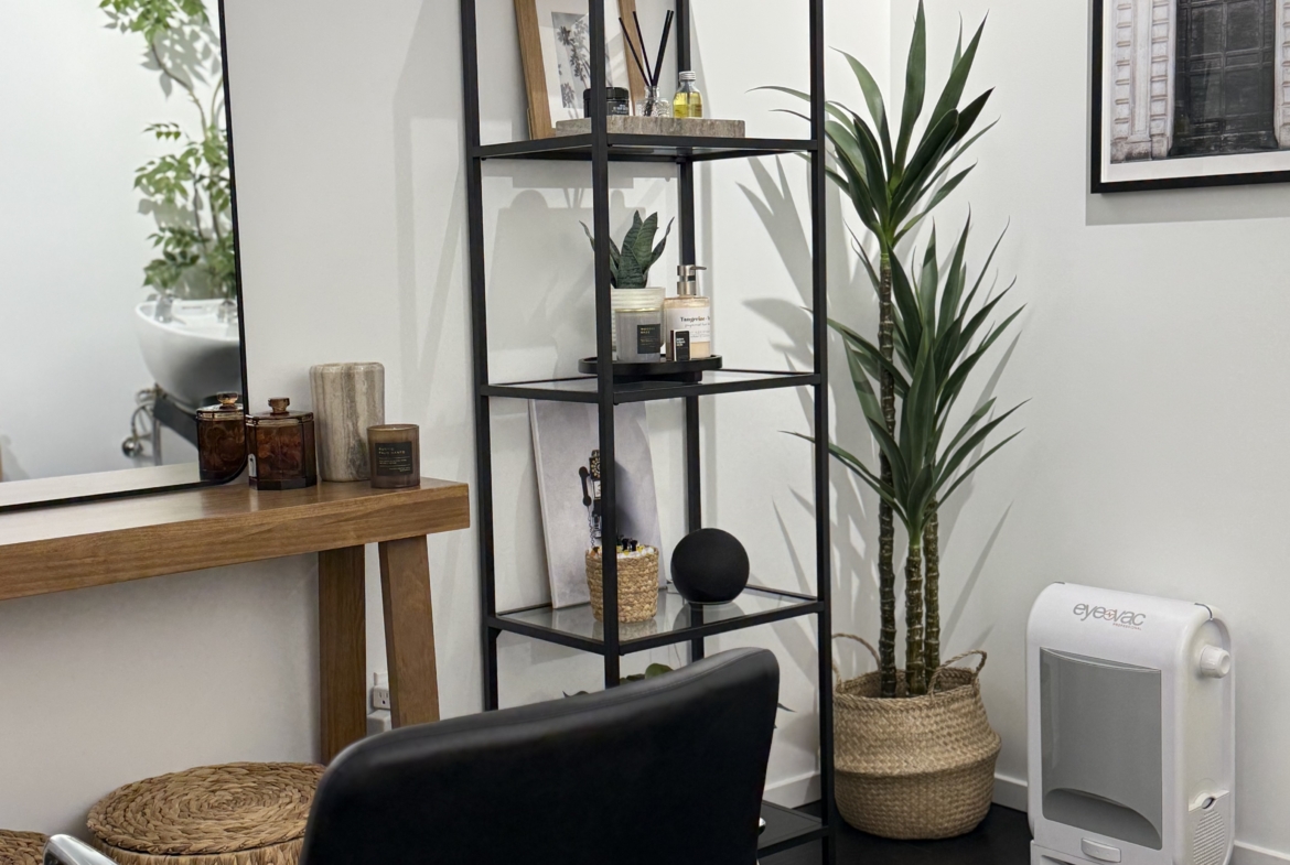 Stylish salon with modern decor, black chair, plant, and shelving for salon rental success.