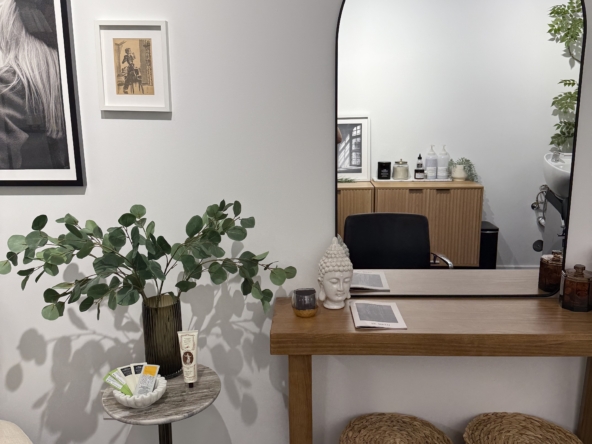 Stylish salon interior featuring a large mirror, seating area, and decorative plants for a welcoming ambiance.