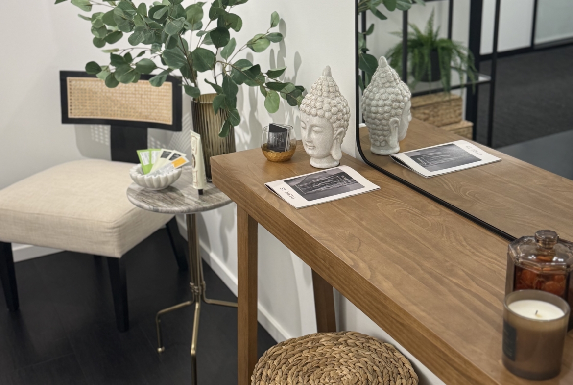 Elegant salon interior featuring a wooden table, greenery, and decorative Buddha statues for a relaxing atmosphere.