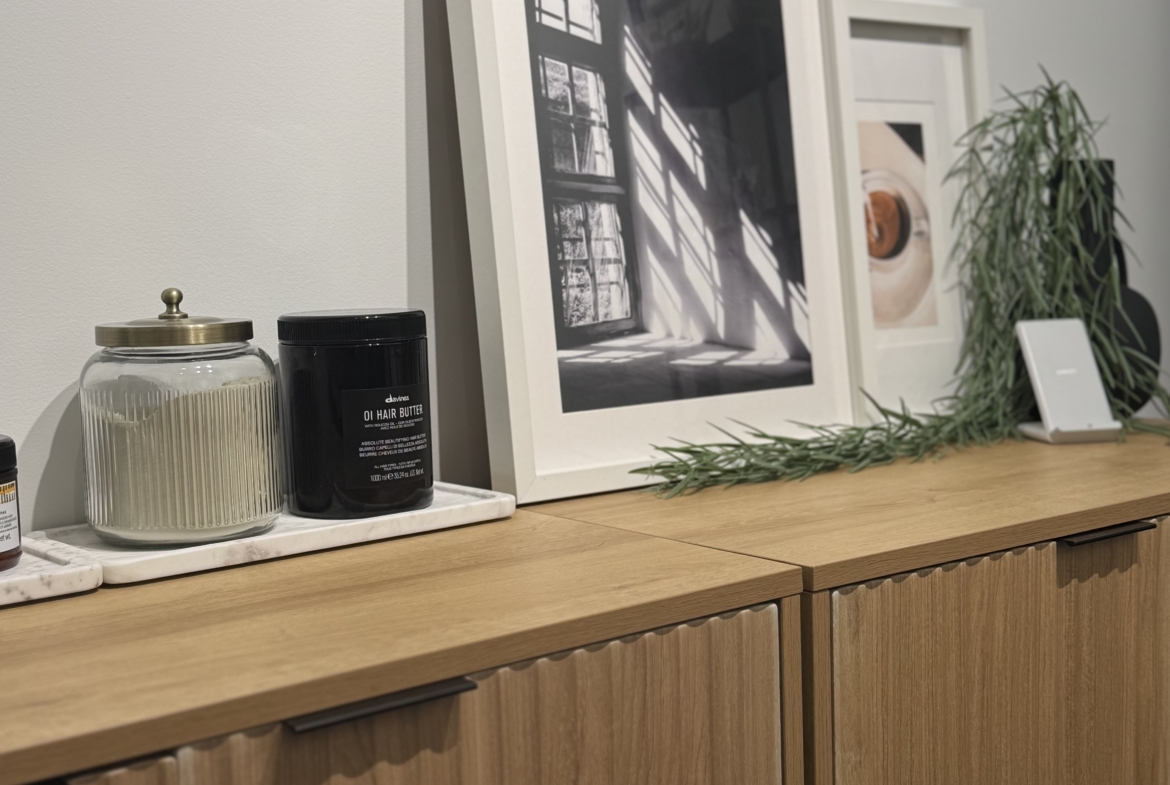 Clean wooden salon cabinet with beauty products, artwork, and natural decor.
