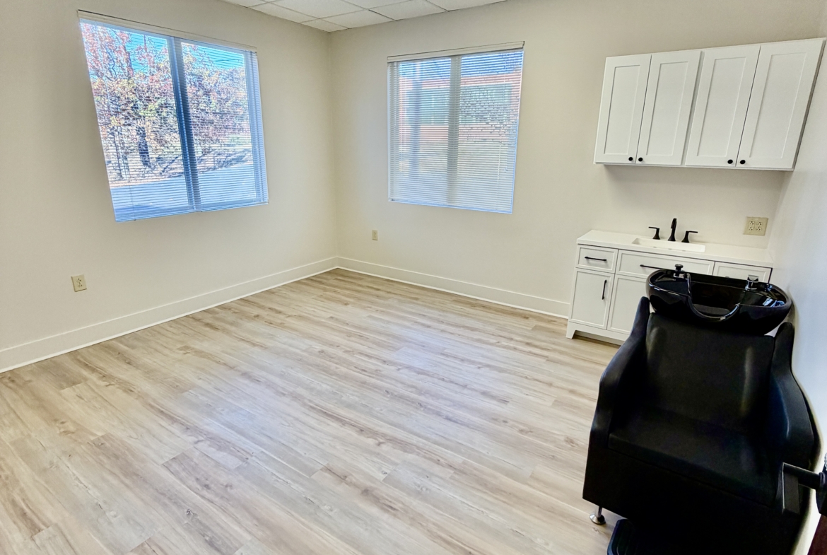 Bright salon rental with windows, white cabinetry, and hair washing sink for hair styling and beauty services.