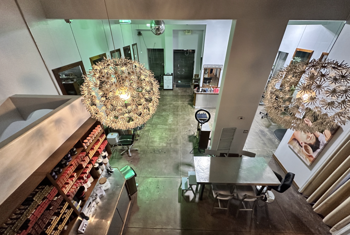 Bright, stylish salon space with chic lighting, workstations, and beauty products for rent.