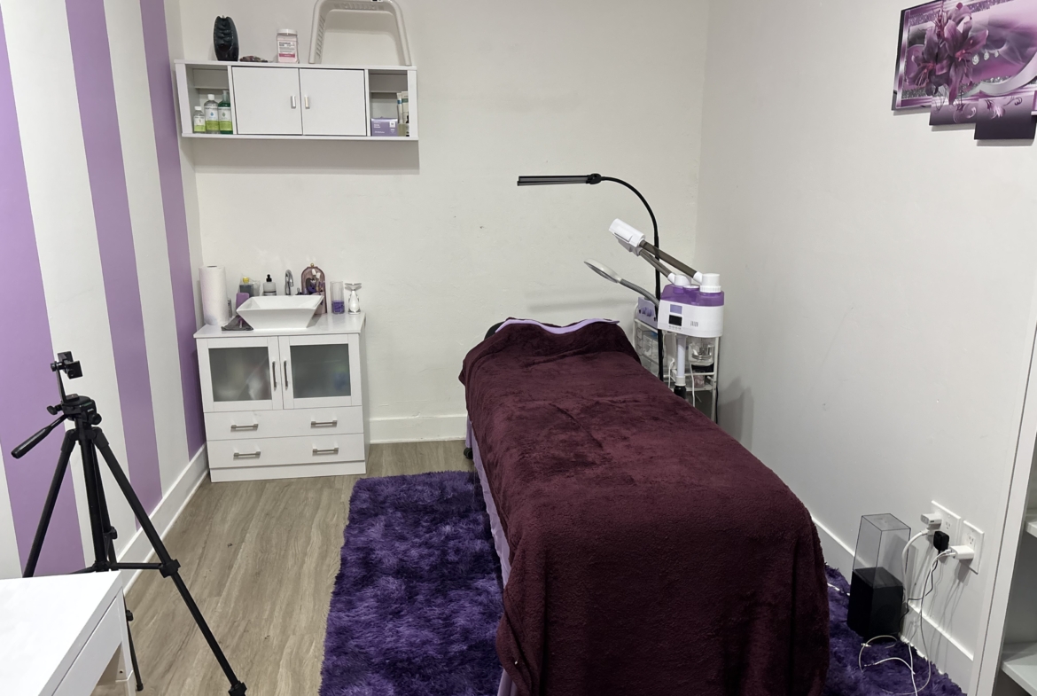 High-quality salon treatment room with massage table, professional equipment, and vibrant purple decor.